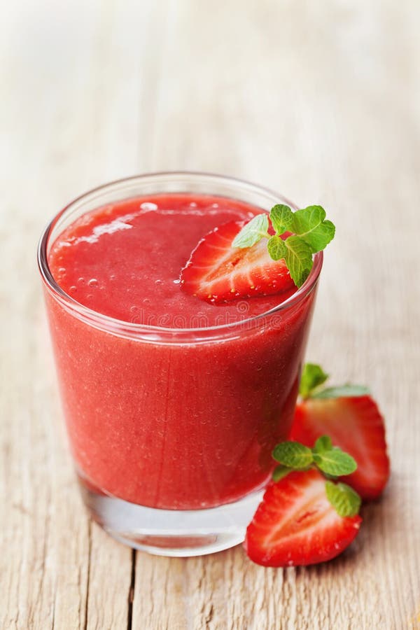 Strawberry smoothie in a glass decorated with mint leaves on rustic background, fresh fruit juice, detox food royalty free stock photography Strawberry smoothie in a glass decorated with mint leaves on rustic background, fresh fruit juice, detox food royalty free stock photography