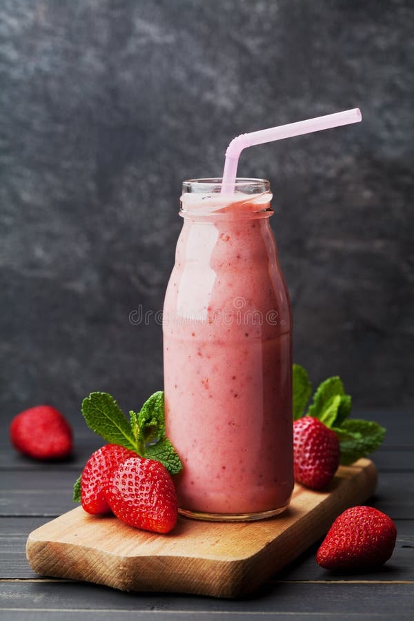 Strawberry smoothie or milkshake in jar on black rustic background, healthy food for breakfast