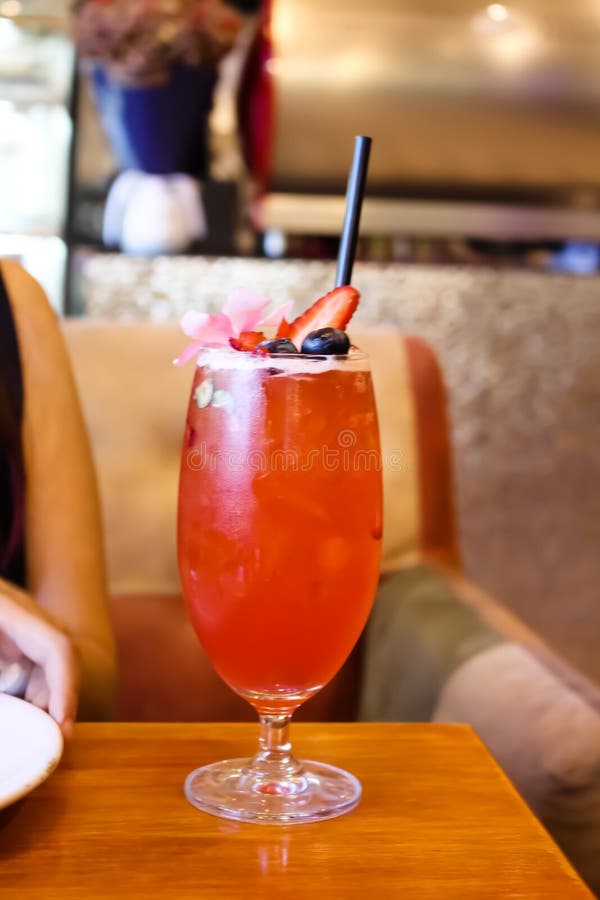Strawberry Thai Iced Tea in Glass with Black Straw on Table Background