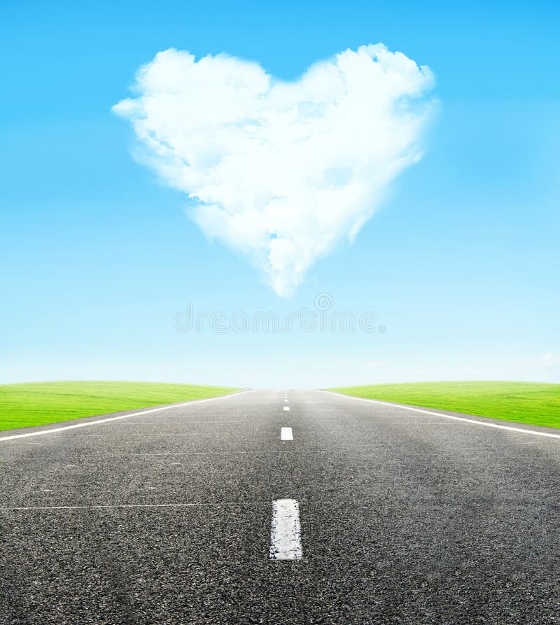 Green field and road over blue sky with clouds in shape of heart - honeymoon travel concept. Green field and road over blue sky with clouds in shape of heart - honeymoon travel concept