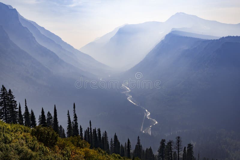 A Mountain Valley With A Valley In The Distance And Fog In The Air