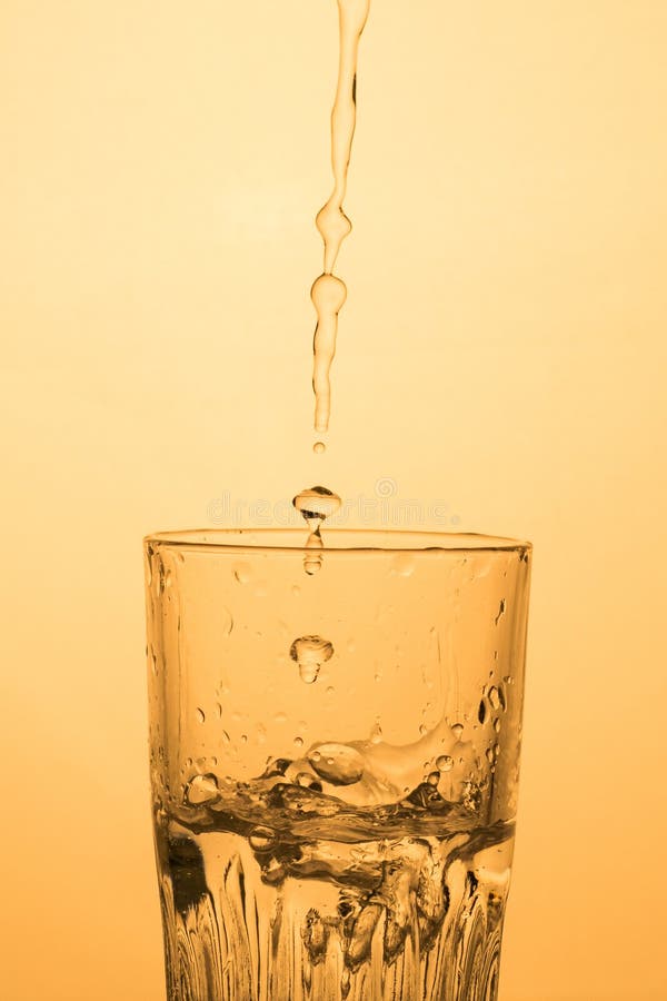 A Stream of Water or Vodka is Pouring into a Glass with Splashes, Warm