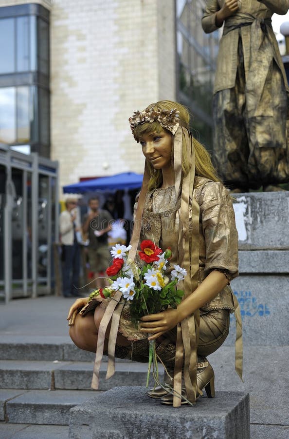 Street actor, young girl, with bouquet of flowers in hands performing on the street stock image Street actor, young girl, with bouquet of flowers in hands performing on the street stock image