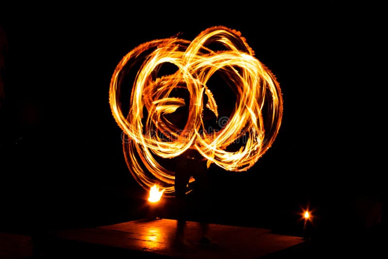 Street artist fire juggling performance. Light painting and long exposure picture to form trails. Phi Phi Island, Thailand.