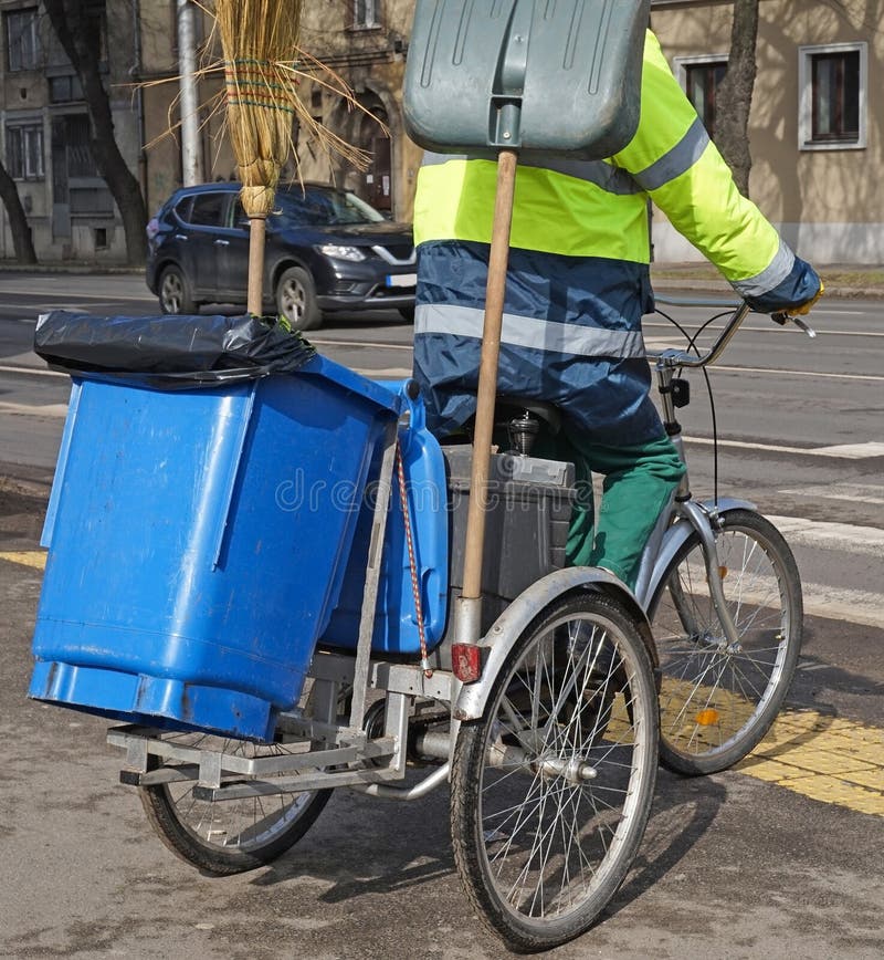 Street cleaner man on bicycle with garbage can stock images