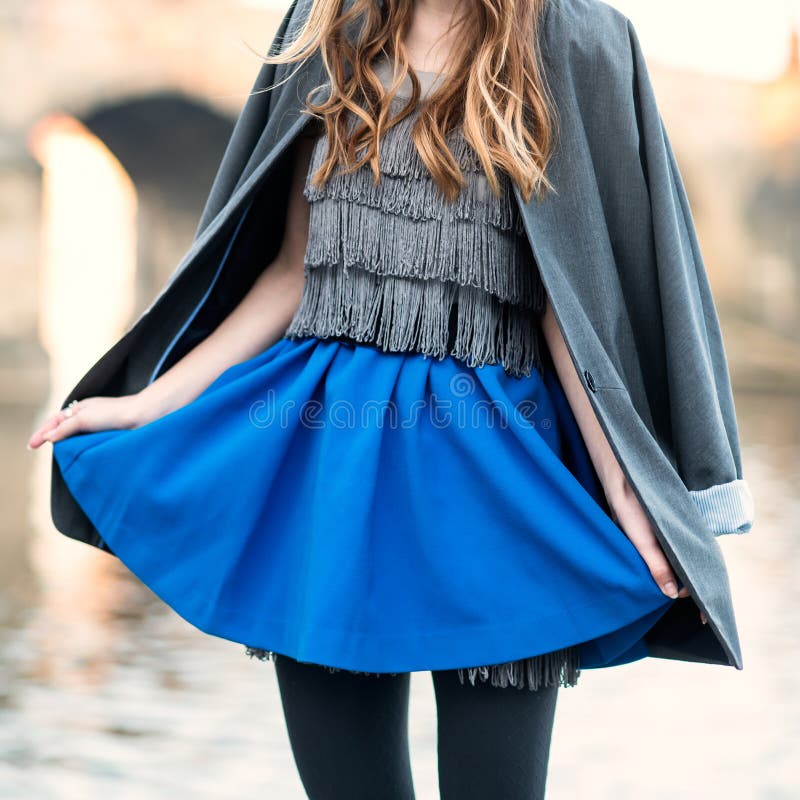 Woman street fashion look with blue skirt, jacket, dress and black tights