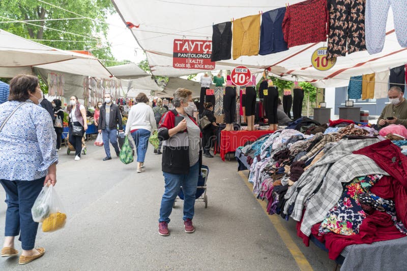 A street market selling clothes and textile. Shopping people wearing medical face masks