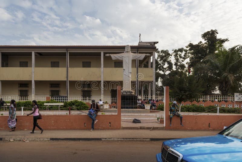 Street scene in the city of Bissau people walking in a sidewalk in front of a church, in Guinea-Bissau