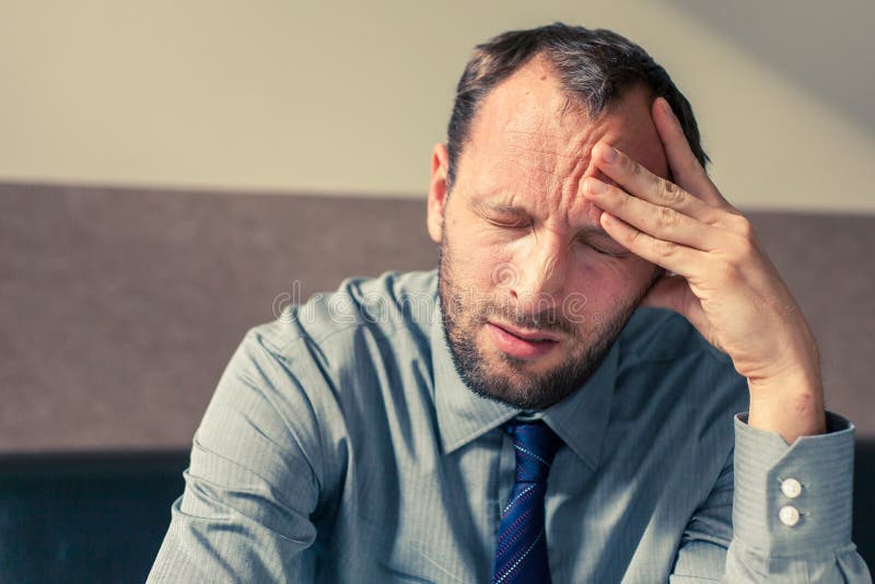 Stressed businessman getting a headache at home in the living room. stock photo