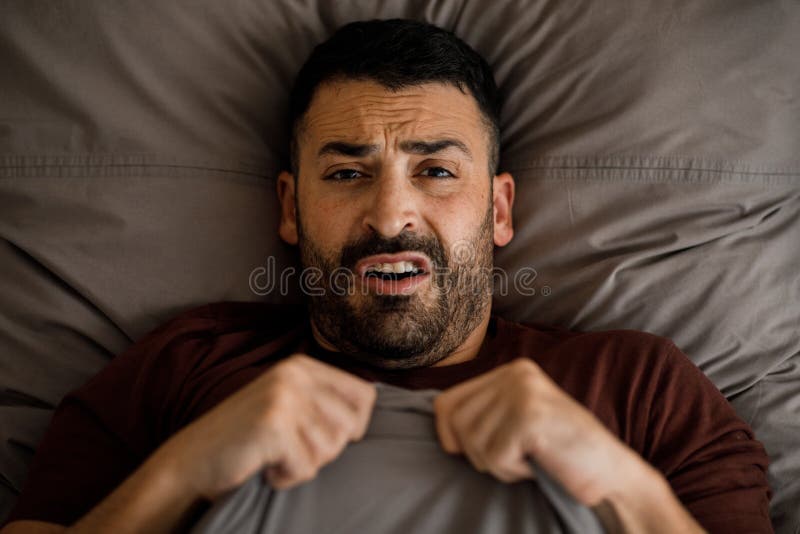 Stressed Middle Eastern Guy Suffering from Insomnia or Headache while Lying in Bedroom at Home