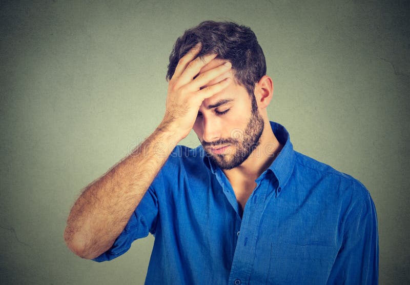 Stressed sad young man looking down on gray wall background royalty free stock photo
