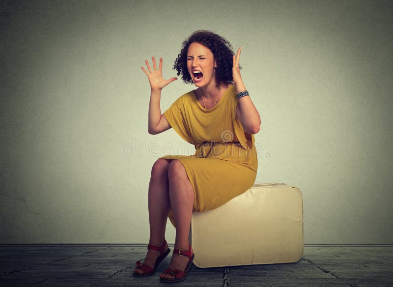 Stressed woman sitting on a suitcase screaming in frustration. royalty free stock photo Stressed woman sitting on a suitcase screaming in frustration. royalty free stock photo