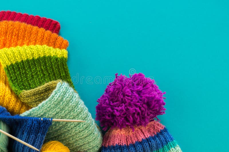 Stricken eines Regenbogenschal und -hut Blauhintergrundes lizenzfreies stockbild Stricken eines Regenbogenschal und -hut Blauhintergrundes lizenzfreies stockbild