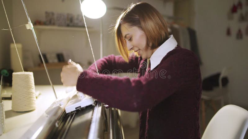Strickendes Gewebe der jungen Frau auf Webstuhlmaschine in der Textilwerkstatt