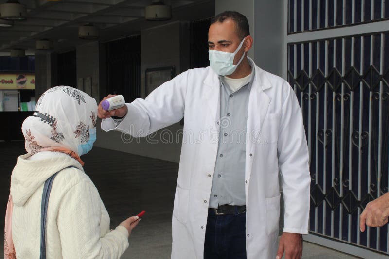 Strict precautionary measures before a building entry, temperature screening, face masks, hand gels stock photo