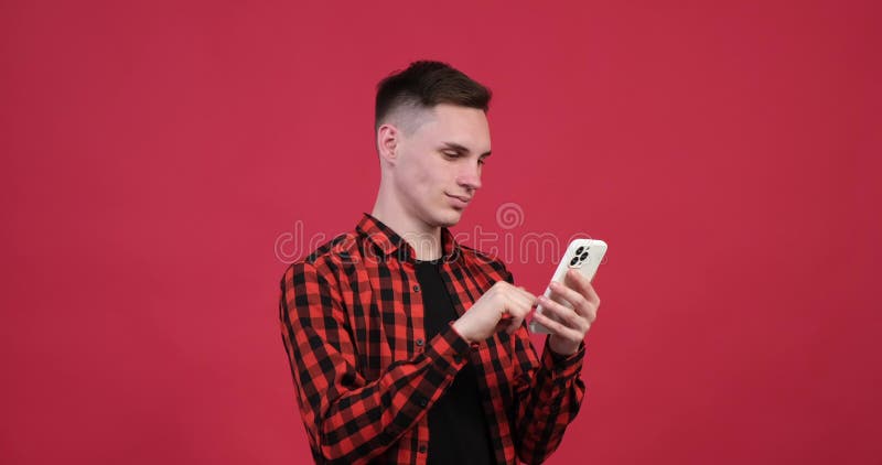 Bărbat caucazian entuziast care se plimbă la telefon pe fond roșu stock footage