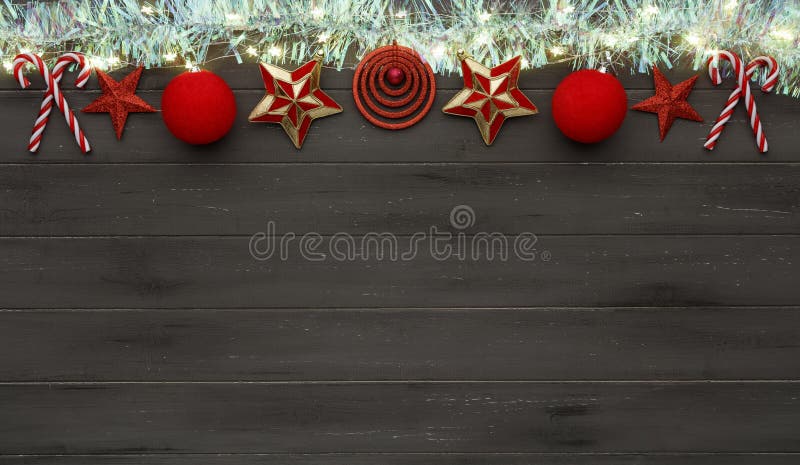 A string of golden star christmas lights, christmas baubles and tinsel on a destressed wooden background, with room for copy space