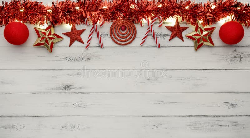 A string of golden star christmas lights christmas baubles and tinsel on a destressed wooden background, with room for copy space