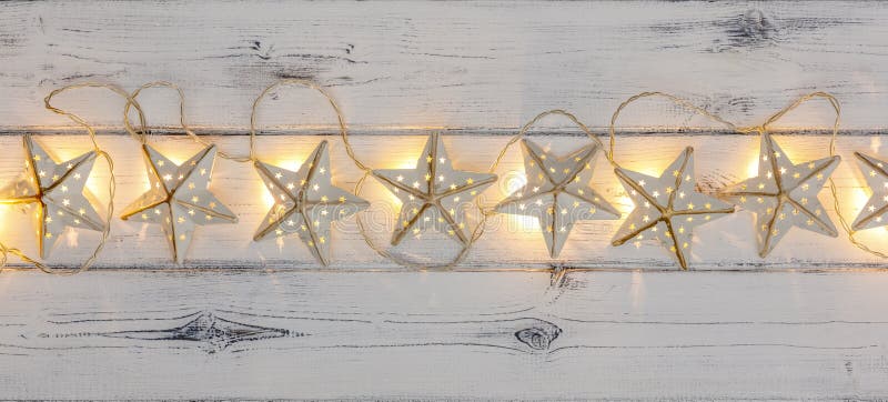 A string of golden star christmas lights, on destressed wood