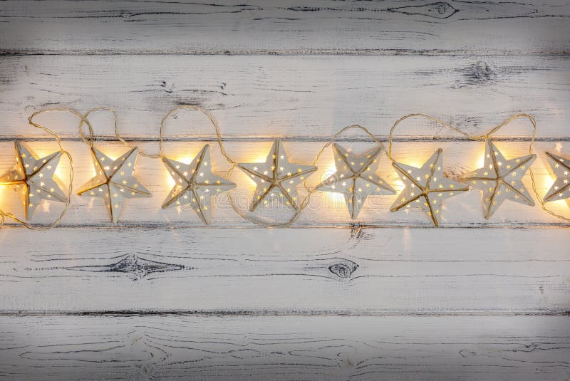 A string of golden star christmas lights, on a destressed woodern background