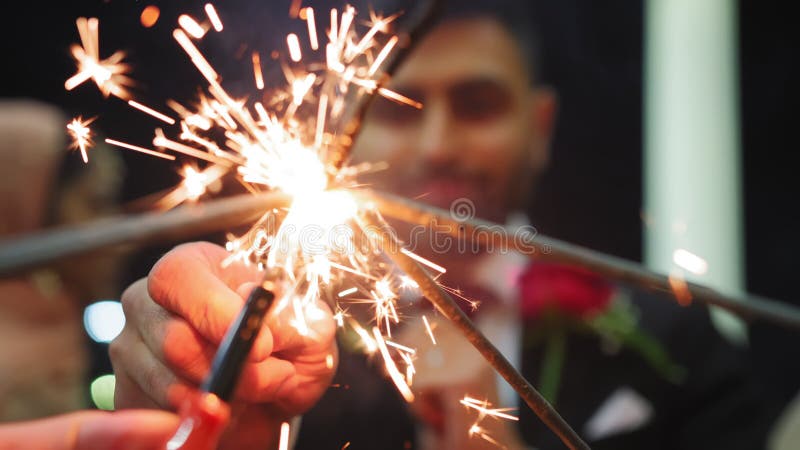 Stringere le mani tenendo in mano un gruppo di amici che festeggiano matrimoni agitando fuochi d'artificio o