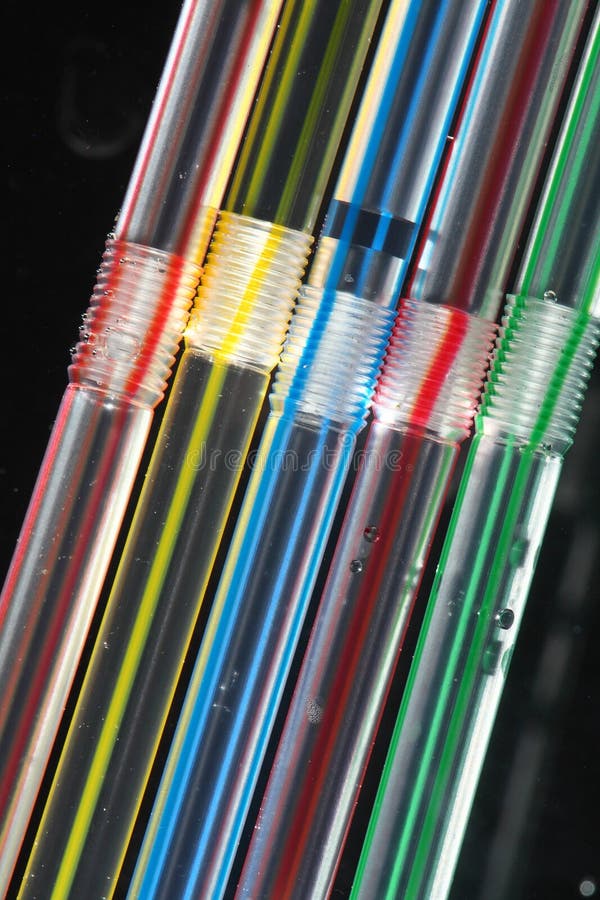 Closeup abstract view of five striped drinking straws arranged in a row vertically at a slight angle, isolated against a black background. Clear closeup view stock images, royalty-free photos and pictures