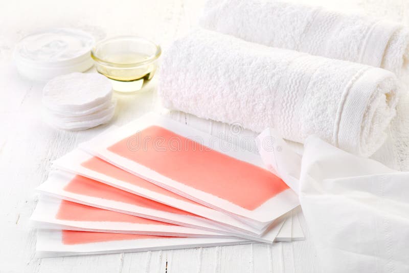 Pink waxing strips, cream and body oil on white wooden background. Pink waxing strips, cream and body oil on white wooden background