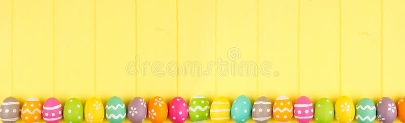 Striscione pasquale colorato con un bordo a righe di uova di Pasqua su uno sfondo di legno giallo con spazio di copia