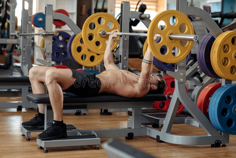 Strong athletic young man bodybuilder fitness model exercise chest with barbell on the bench in gym. stock photography Strong athletic young man bodybuilder fitness model exercise chest with barbell on the bench in gym. stock photography