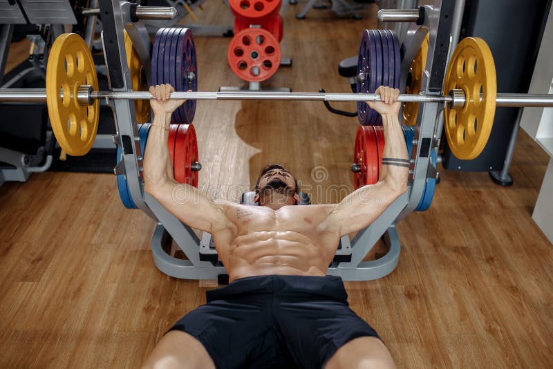 Strong athletic young man bodybuilder fitness model exercise chest with barbell on the bench in gym. Top view. royalty free stock photo Strong athletic young man bodybuilder fitness model exercise chest with barbell on the bench in gym. Top view. royalty free stock photo