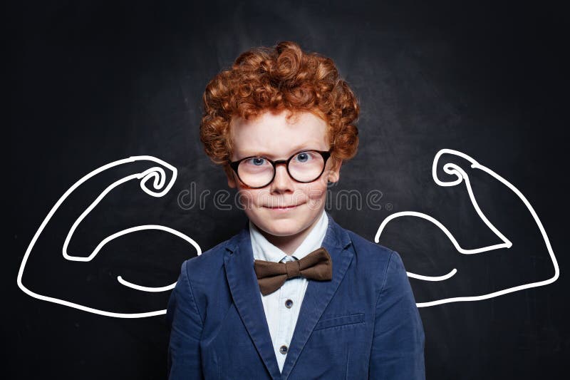 Strong child in blue suit, bow tie and glasses on chalkboard background