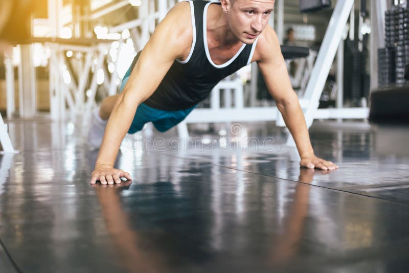 Strong man doing push up and exercises on floor at gym