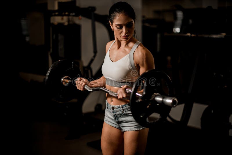 Side view of muscular female in sportswear holding barbell on shoulders and  squatting during workout in gym Stock Photo - Alamy