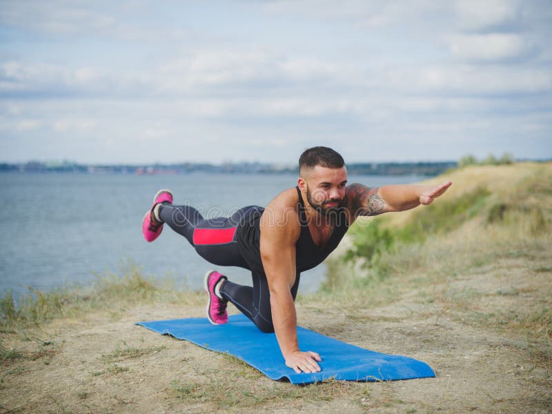 Portrait of gorgeous young male, practicing yoga outdoors. Outside training under morning sun.