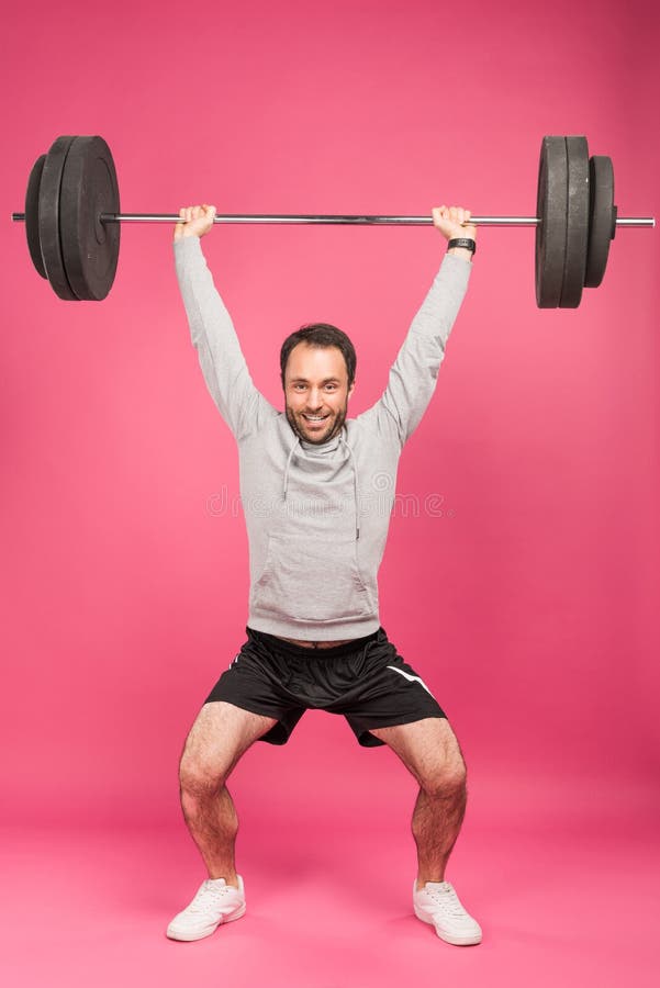strong sportsman training with barbell, isolated on pink