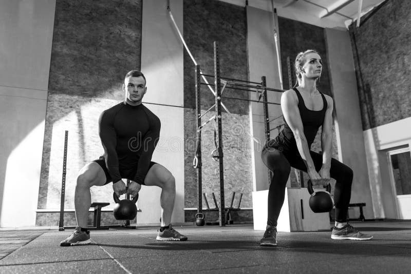 Strong well built man and woman holding kettlebells