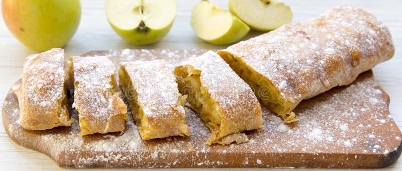 Strudel or apple pie on wooden board, side view.