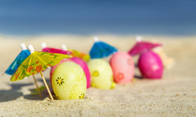 Struttura (fondo) con le uova di Pasqua variopinte con gli ombrelli sulla spiaggia con il mare fotografia stock Struttura (fondo) con le uova di Pasqua variopinte con gli ombrelli sulla spiaggia con il mare fotografia stock