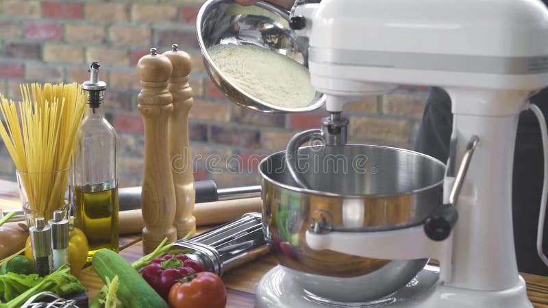 Strömendes Mehlpulver des Bäckers im Mischer für knetenden Teig in der Bäckerei Kochen Sie strömendes Mehl in der Küchenmaschine