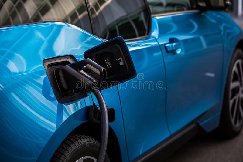 Power supply for electric car charging. Electric car charging station. Close up of the power supply plugged into an electric car being charged. Power supply for electric car charging. Electric car charging station. Close up of the power supply plugged into an electric car being charged.