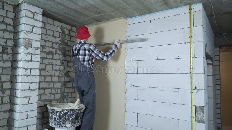 Stucco wyrównawczy budowniczy profesjonalny na napowietrzonej ścianie bloku betonowego