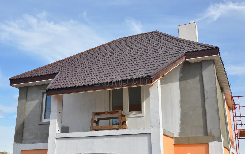 Stucco and painting house wall during renovation. Roofing Construction with Soffit installation. Close up on painting house wall. Stucco and painting house wall during renovation. Roofing Construction with Soffit installation. Close up on painting house wall.