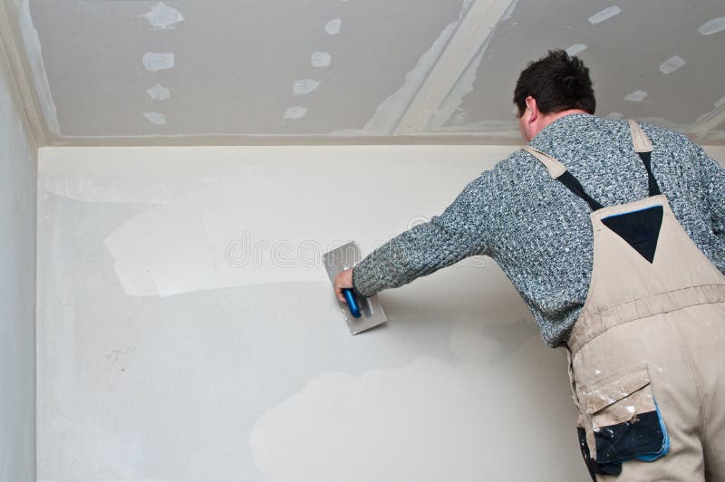 Plasterer or dry waller male worker at work, finishing interior wall. Plasterer or dry waller male worker at work, finishing interior wall.