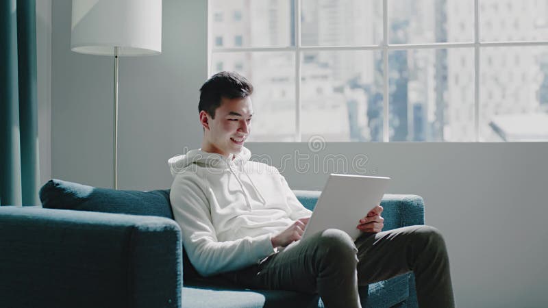 Student chats with friends typing on tablet at room window