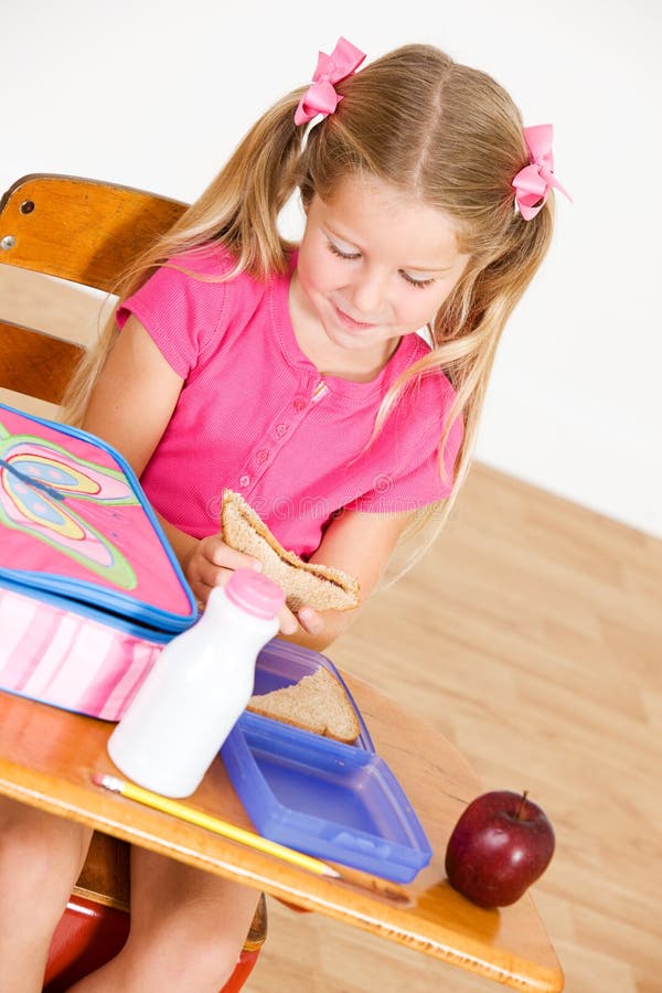 Student: Das hungrige Mädchen sitzt am Schreibtisch das Mittagessen essend stockfoto Student: Das hungrige Mädchen sitzt am Schreibtisch das Mittagessen essend stockfoto