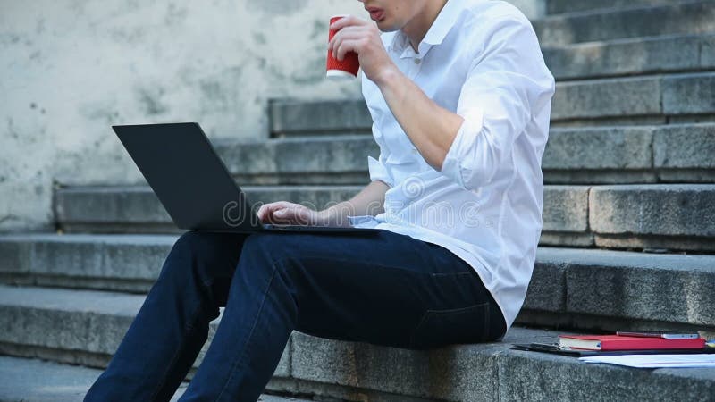 Student, der auf die Treppe sitzt und auf Notebook schreibt.