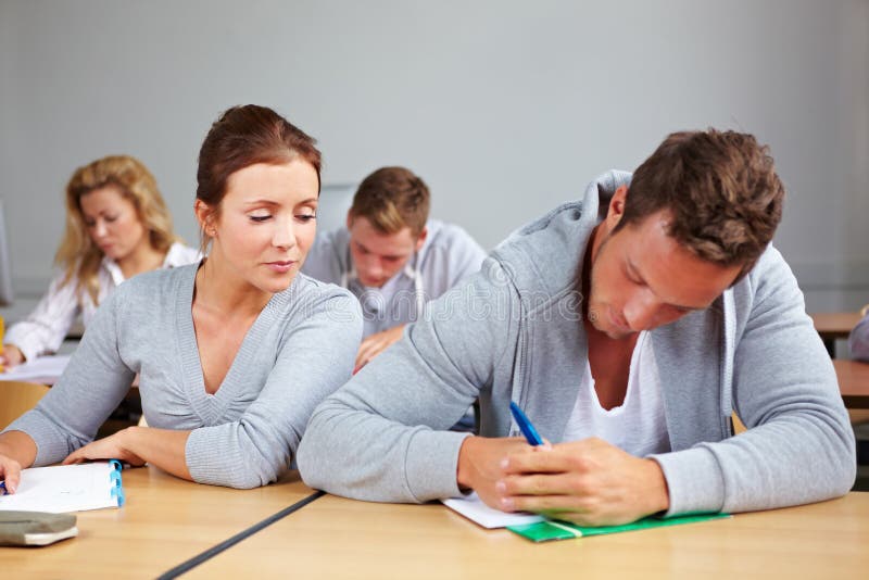 Female student trying to cheat at test in class. Female student trying to cheat at test in class