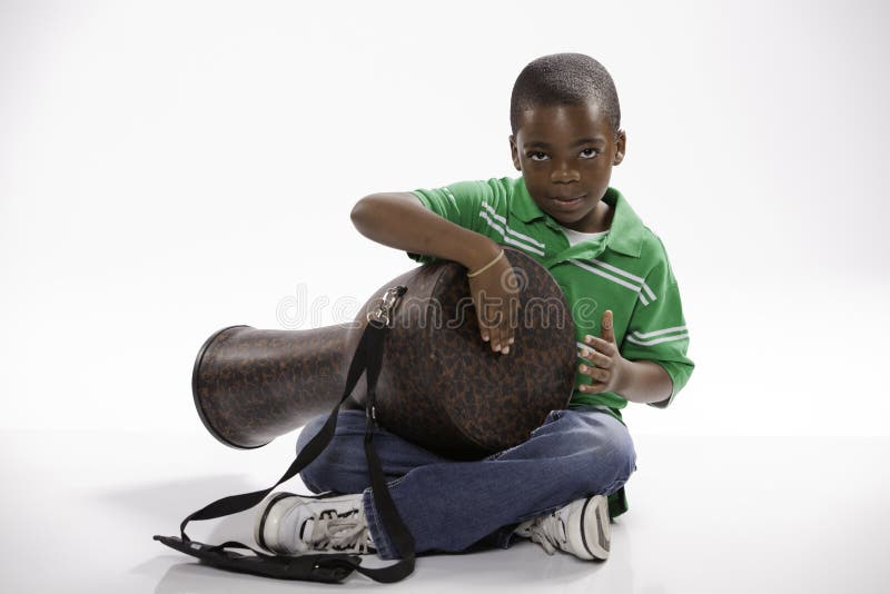 Eine kleine, isolierte African American männliche Kind, das in einem grünen Hemd zu studieren, zu spielen wie eine djembe-Trommel auf weißem hintergrund.