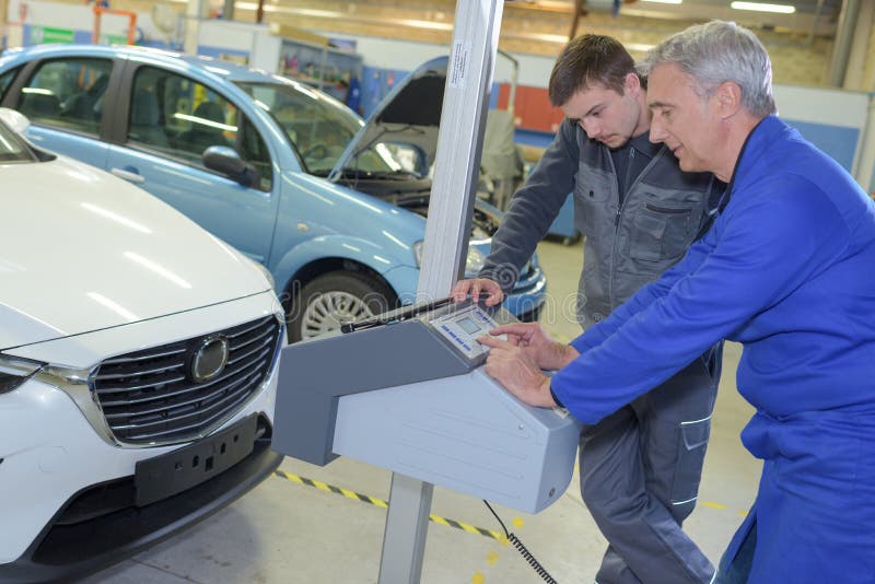 Student with Instructor Repairing Car during Apprenticeship Stock Photo