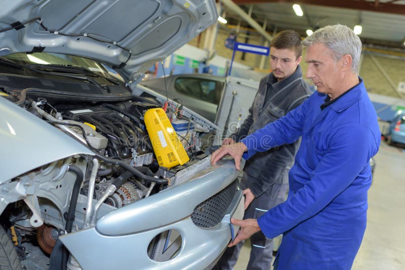 Student with Instructor Repairing Car during Apprenticeship Stock Photo